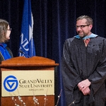 Christine Rener converses with colleague during convocation ceremony on stage